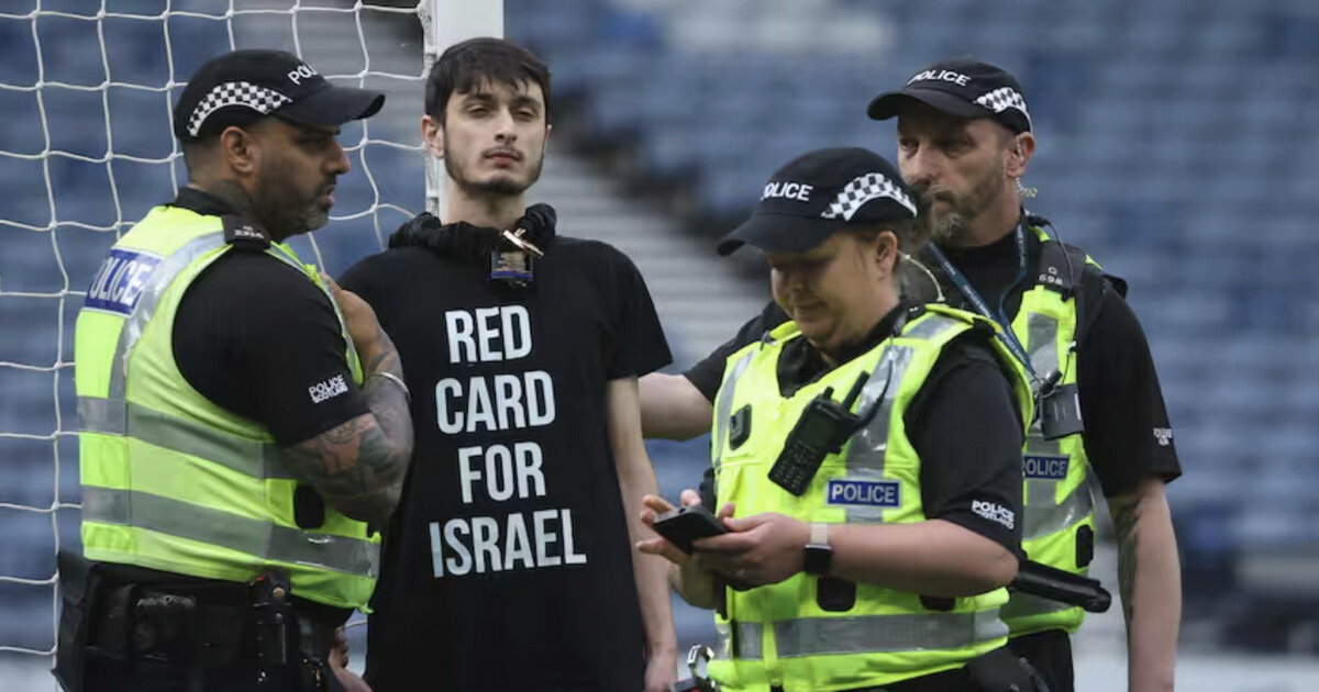 Пропалестинский активист в футболке с текстом Красная карточка Израилю приковал себя к воротам перед игрой женской сборной Израиля в Шотландии