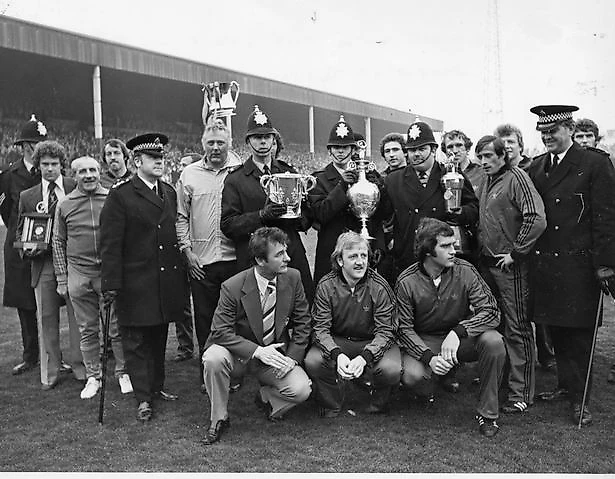 Брайан Клаф, Питер Тейлор и игроки демонстрируют с полицейскими кубок лиги и кубок чемпионата