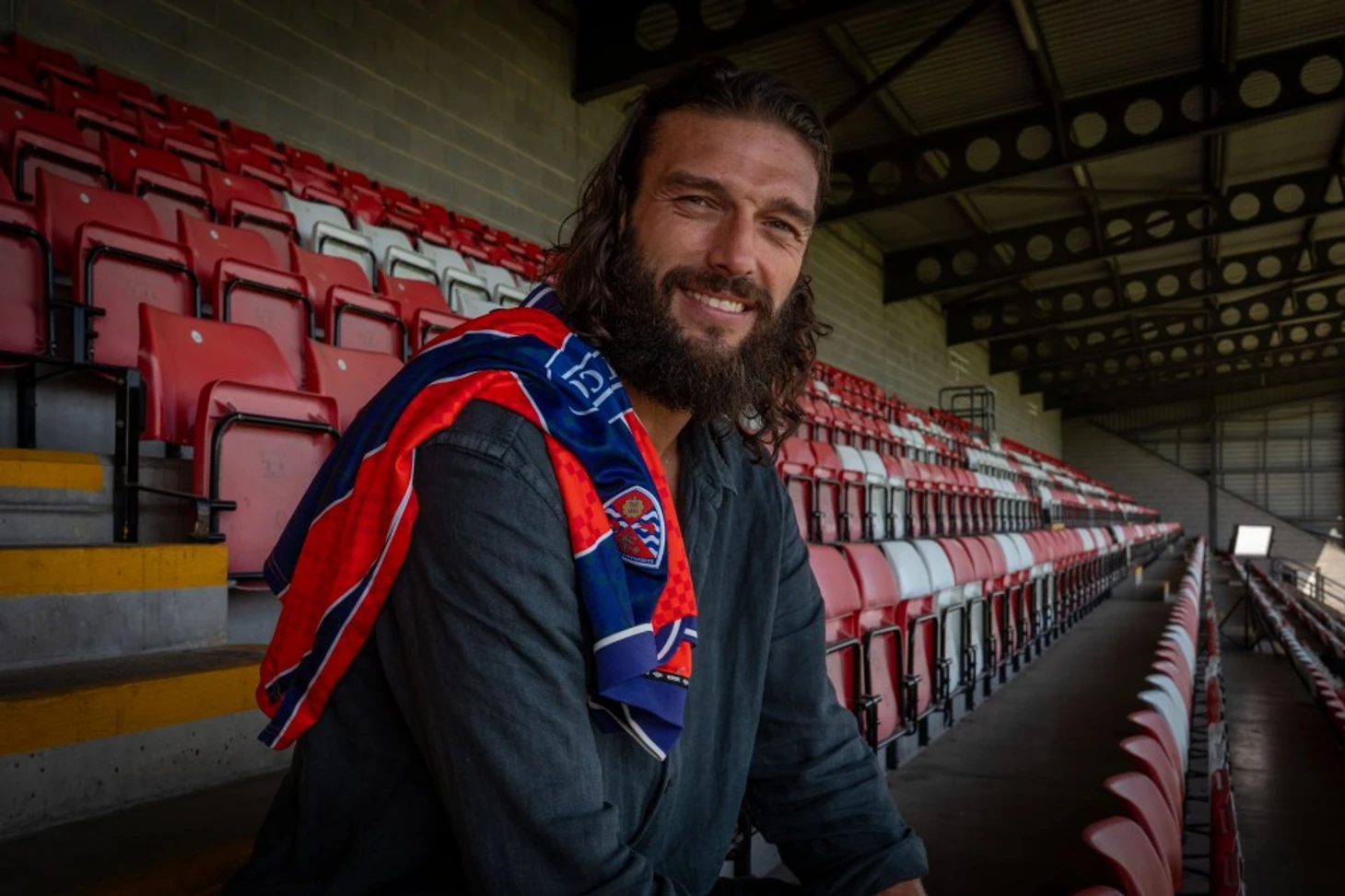 Andy Carroll, former Newcastle, West Ham, and England footballer, sitting in stadium seats.